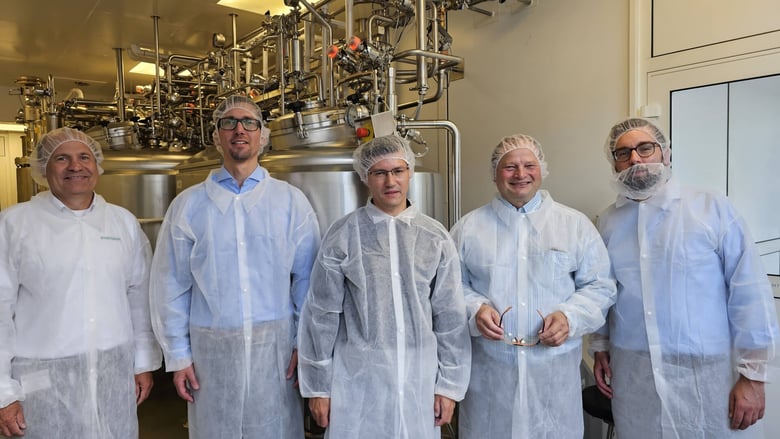 Team members in protective clothing standing in a production facility