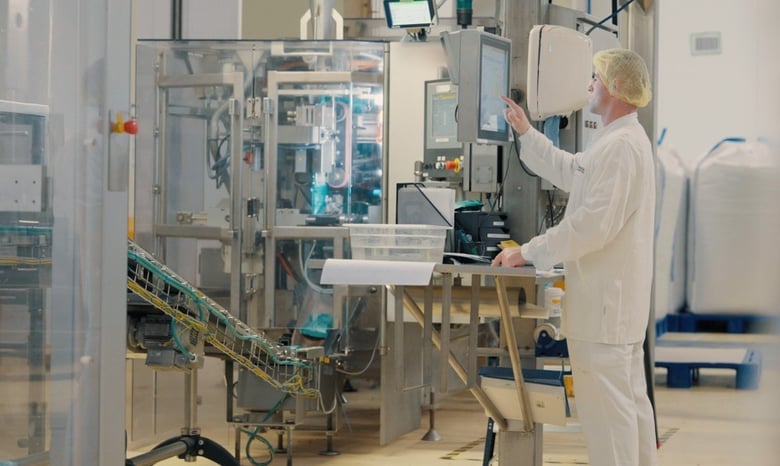 Automated production line with operator interacting via HMI panel.