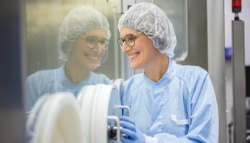 Pharmaceutical professional in sterile gown operating RTU equipment, showcasing Syntegon's compliance with GMP and Annex 1 global standards for safe production