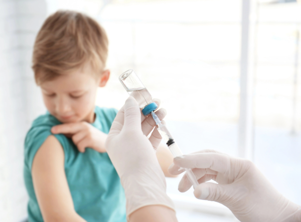 Healthcare professional administering a vaccine to a child, showcasing the role of Syntegon's RTU systems in ensuring safe and sterile biologics processing
