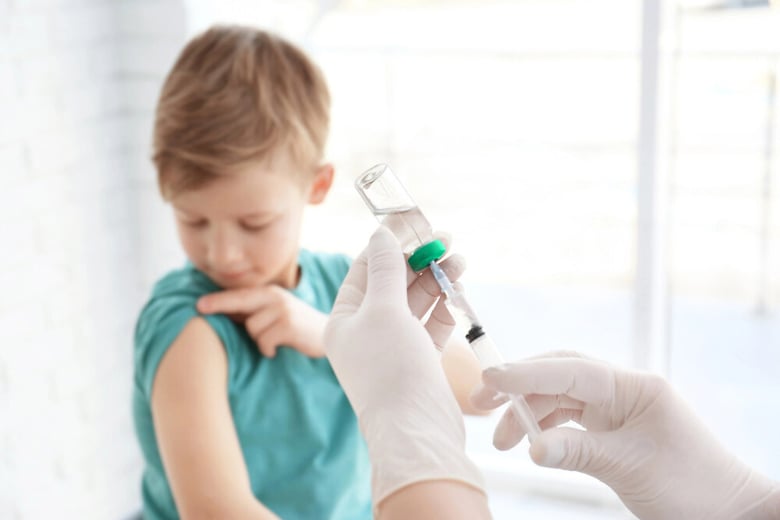 Healthcare professional administering a vaccine to a child, showcasing the role of Syntegon's RTU systems in ensuring safe and sterile biologics processing