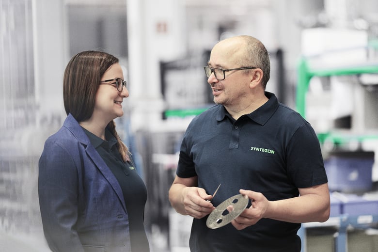 Syntegon employees discussing spare parts in a production environment.