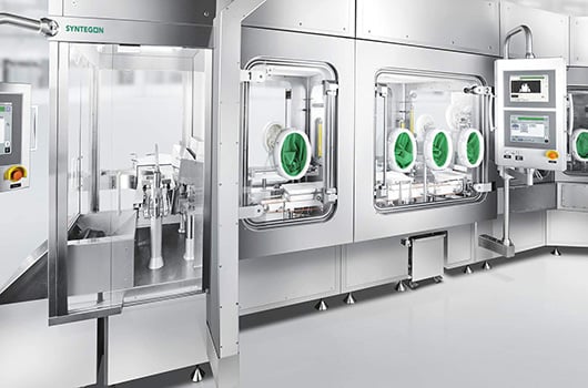 Syntegon pharmaceutical isolator line with green glove ports and dual touchscreen HMIs for precise aseptic filling and containment