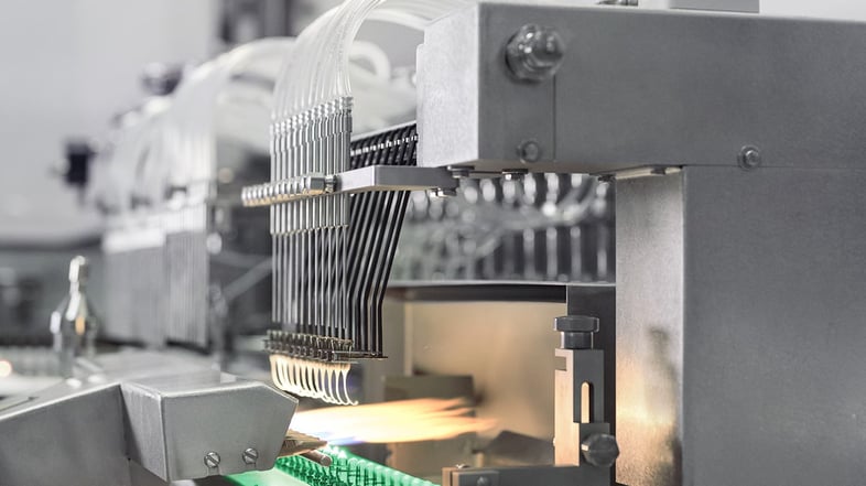 Close-up of an ampoule filling machine performing high-precision sealing with flame technology, ensuring sterile closure of pharmaceutical ampoules in aseptic environments.