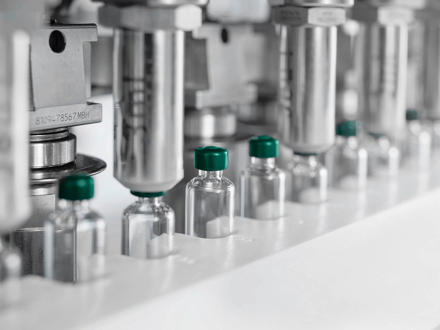Glass cartridges with green caps in an automated filling line